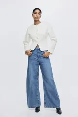Blazer de botonadura sencilla en tejido efecto neopreno color blanco. Modelo de hombros caídos con escote redondo, botones hasta la cintura y corte acampanado de cintura a bajo.