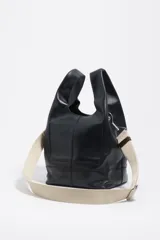 Bolso de mano Bimba y Lola modelo Paper mediano, confeccionado en cuero color tostado con estructura blanda, asas superiores y correa de hombro ajustable en color beige. Presenta costuras visibles, logo metálico de la marca en la parte inferior y cierre principal.