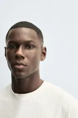 Camiseta de manga corta y cuello redondo, color blanco roto, con textura seersucker.