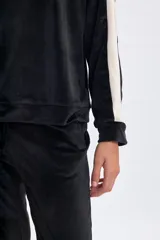 Buzo de plush color negro con cuello alto y franjas laterales en color beige en las mangas. Presenta un diseño holgado y cómodo.