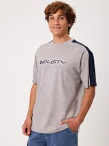 Remera negra de manga corta con diseño deportivo, parte superior de las mangas en color gris con ribete blanco y estampa frontal con la marca Rusty.