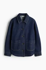 Campera camisera en denim rígido color azul, con cuello camisero, cierre frontal de botones, bolsillos de parche delanteros y bajo redondeado.