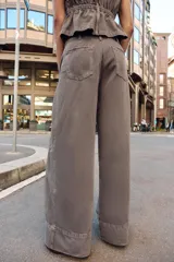 Jeans de tiro medio con corte wide leg y pernera ancha. Presenta pinzas delanteras, bolsillos frontales, bolsillos de plastrón en la espalda y cierre frontal con cremallera, botón interior y ganchos metálicos.