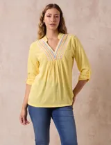 Blusa amarilla de manga 3/4 con escote en V y bordado multicolor. Largo de manga regulable con presilla y botón. Marca Ruby Rd.