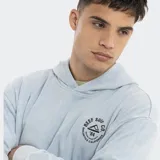 Canguro con capucha de estilo urbano, color celeste con efecto lavado. Presenta un estampado circular pequeño en el pecho con el logo de Reef Surf Co. y bolsillo tipo canguro frontal.