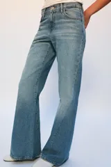 Jeans de tiro bajo con corte flare y diseño de cinco bolsillos. Presentan un acabado con efecto lavado y bajo evasé, con cierre frontal de cremallera y botón.