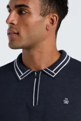 Sweater de tejido de punto color azul marino, manga larga, con cuello polo y cierre frontal parcial con cremallera. El cuello y los puños tienen un ribete de doble línea blanca. Presenta un pequeño logo bordado en el pecho.