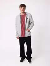 Campera canguro de felpa color gris claro melange, con capucha ajustable mediante cordones negros, cierre frontal completo, bolsillos tipo canguro y parche con logo de la marca en el pecho.