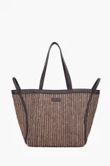 Bolso tipo tote de rafia trenzada en tonos marrones y beige, con asas largas y detalles en cuero sintético marrón oscuro. Cuenta con un pequeño parche con la marca grabada en la parte frontal.