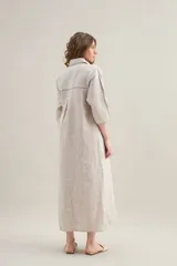 Vestido largo lila de lino, con cuello camisero, mangas cortas, bolsillos frontales con costuras a contratono y aberturas laterales.