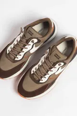 Zapatillas deportivas color crema con detalles en beige, negro y blanco.