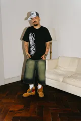 Bermuda de jean estilo baggy con lavado verde desgastado. Presenta grandes bolsillos traseros con bordados en hilo rojo que simulan caracteres chinos.