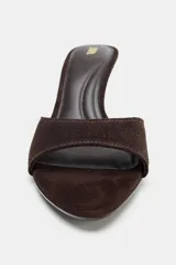 Sandalia tipo mule de tacón fino alto, confeccionada en serraje de color marrón con tira delantera ancha y punta redonda.