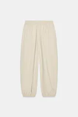 Pantalón de tiro medio y cintura elástica con cordón de ajuste, bolsillos laterales y bajo abullonado con puños elásticos. Confeccionado en poliamida.