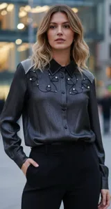 Camisa de manga larga en color gris oscuro con acabado brillante. Presenta un cuello clásico con apliques de pedrería, detalles bordados con líneas curvas y perlas decorativas en el frente, y paneles texturizados en los hombros.