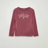 Conjunto de pijama de dos piezas color rosa, compuesto por una camiseta de manga larga con estampado frontal de la palabra "Jolie" y un pantalón largo.