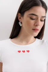 Remera azul marino de algodón con cuello redondo y mangas cortas. Tiene tres corazones rojos bordados en el pecho.