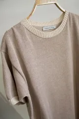 T-shirt de tejido artesanal color rojo intenso, con cuello redondo y bordes en color marrón. Presenta mangas cortas y un calce holgado.