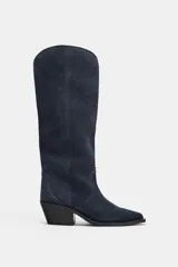 Bota alta de estilo cowboy confeccionada en serraje de color azul marino, con tacón medio en bloque y puntera perfilada. Presenta costuras decorativas en el cuerpo y diseño de calce fácil.