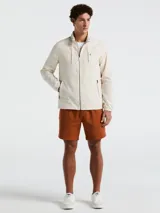 Campera rompevientos color crema con cierre frontal, cuello alto, capucha oculta, puños elásticos y bolsillos laterales con cierre.