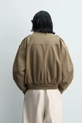 Cazadora de corte cropped fit, color verde oliva, confeccionada en mezcla de viscosa y algodón. Presenta cuello subido, manga larga, trabillas en los hombros, bolsillos de plastrón con solapa en la cadera y cierre frontal con cremallera.