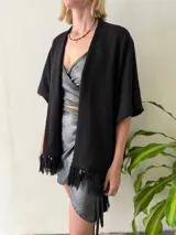 Ruana tejida color negro, con flecos en los extremos.