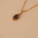 Collar de oro 18k con cadena fina de eslabones y dije ovalado central que presenta un zafiro azul rodeado por pequeños brillantes.