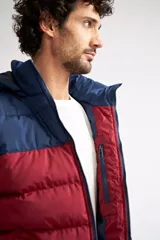 Campera puffer de nylon con diseño bicolor en negro y verde oliva. Cuenta con cierre frontal completo, capucha desmontable y logo de la marca estampado en el pecho.