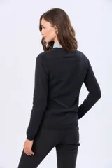 Buzo tejido en hilo de algodón color beige, con cuello redondo y manga larga. Presenta un corte clásico y un pequeño detalle metálico en la parte inferior izquierda.