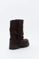 Bota de caña media con flecos laterales, confeccionada en material con textura tipo gamuza. Presenta una silueta relajada y suela robusta con base dentada.