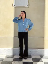 Camisa de jean celeste con cuello redondo, cierre frontal con botones y mangas largas abullonadas con puños ajustados.