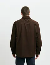 Sobrecamisa de pana color marrón, con manga larga, cierre frontal con botones y dos bolsillos frontales con solapa y botón.