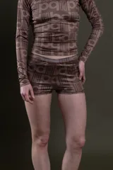 Short de lycra color marrón con estampado de letras y figuras geométricas en tonos más oscuros.