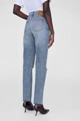 Jean celeste de tiro alto, corte recto y ajustado al tobillo, con roturas en las rodillas y terminación desflecada.