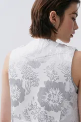 Chaleco de brocato blanco con diseño de flores plateadas, calce entallado y botones ocultos en el frente.