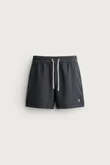 Bermuda relaxed fit de color gris oscuro, confeccionada en tejido de algodón con textura estructurada. Cuenta con cintura elástica ajustable con cordón blanco en contraste, bolsillos laterales y pequeño detalle bordado en la pernera.