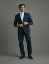 Saco de vestir azul oscuro con textura sutil, corte entallado, cierre frontal de un botón y solapas clásicas.