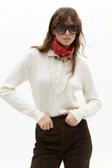 Sweater tipo polo color blanco roto, tejido en ochos, con cuello clásico y media cartera de botones.