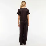 Pijama de dos piezas compuesto por una camisa de manga corta con volados y cierre frontal con lazos, y un pantalón largo de corte recto. Presenta un estampado animal print sutil en tonos oscuros.