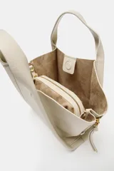 Bolso bandolera de formato city color marrón, con diseño estructurado, pespuntes decorativos, doble asa de mano y cremalleras laterales con tiradores colgantes.