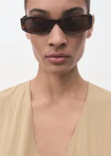 Vestido midi de corte evasé en color beige, con cuello en pico y manga corta. Presenta un diseño con costuras verticales decorativas y cierre de cremallera en la parte posterior.