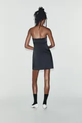 Vestido mini satinado negro con escote palabra de honor y detalle de lazo en el frente.
