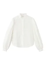 Blusa blanca de algodón con bordados florales, cuello alto con volados y mangas largas abullonadas con puños ajustados.