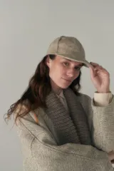 Gorra con visera confeccionada en lana fina sin teñir, con un sutil patrón de tejido en espiga.