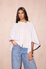 Camisa holgada de algodón con cuello alto y mangas anchas, confeccionada en Italia. Presenta un estampado de rayas verticales finas en tonos beige, blanco, amarillo, rojo y azul.