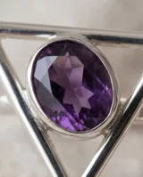 Anillo de plata 925 con diseño geométrico triangular y piedra amatista central de corte ovalado.
