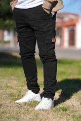 Pantalón cargo negro de corte slim fit, con bolsillos laterales en los muslos y detalles de apliques de cuero.