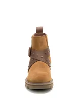 Bota corta de gamuza color marrón, con diseño de caña media y elástico lateral. Presenta una tira de cuero cruzada con hebilla metálica y tachuelas decorativas. Cuenta con suela de goma dentada y logo de la marca grabado en el lateral.