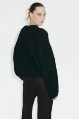 Pantalón amplio de punto bouclé color marrón oscuro, de tiro alto con elástico oculto en la cintura, bolsillos delanteros y cierre con botón.