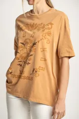 Remera color arena con estampa frontal de flores y texto "Les Tourness Bisou". Corte oversize.